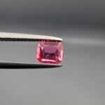 Studio close-up photographs showing the top and facet profile views of a 0.68 carat cushion mixed cut natural rubellite tourmaline loose gemstone held in precision tweezers.
