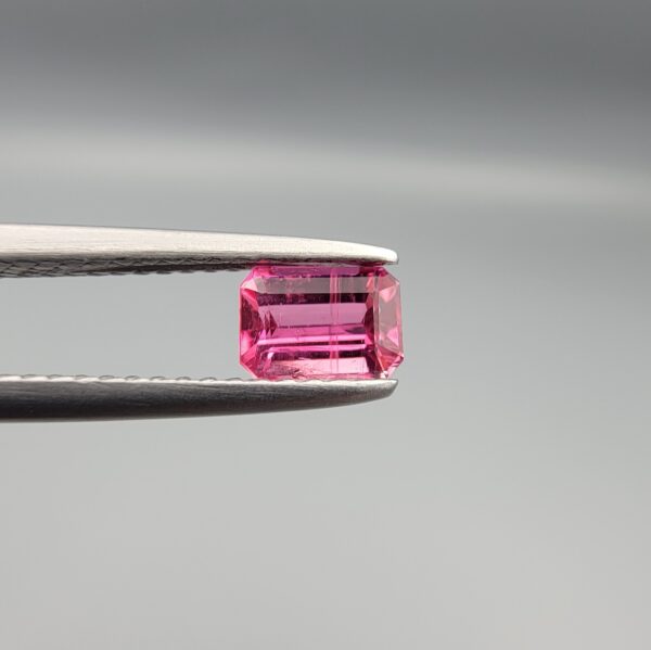 Studio close-up photographs showing the top and facet profile views of a 0.52 carat octagon cut natural rubellite tourmaline loose gemstone held in precision tweezers.