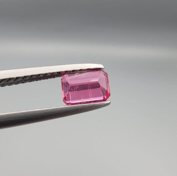 Studio close-up photographs showing the top and facet profile views of a 0.52 carat octagon cut natural rubellite tourmaline loose gemstone held in precision tweezers.