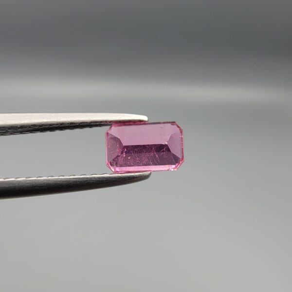 Studio close-up photographs showing the top and facet profile views of a 0.75 carat octagon cut natural rubellite tourmaline loose gemstone held in precision tweezers.