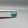Studio close-up photographs showing the top and facet profile views of a 0.51 carat cushion cut natural blue tourmaline loose gemstone held in precision tweezers.