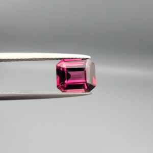 Studio close-up photographs showing the top table face, step-cut pavilion facets, and reverse profile views of a 3.17 carat cushion cut natural rhodolite garnet loose gemstone held in precision tweezers.