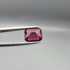 Studio close-up photographs showing the top table face, step-cut pavilion facets, and reverse profile views of a 3.17 carat cushion cut natural rhodolite garnet loose gemstone held in precision tweezers.