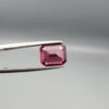Studio close-up photographs showing the top table face, step-cut pavilion facets, and reverse profile views of a 3.17 carat cushion cut natural rhodolite garnet loose gemstone held in precision tweezers.