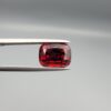 Studio close-up photographs showing the top table face, step-cut pavilion facets, and reverse profile views of a 4.55 carat cushion cut natural almandine garnet loose gemstone held in precision tweezers.