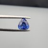 Studio close-up photographs showing the top table and facet profile views of a 1.26 carat pear cut natural blue sapphire loose gemstone held in precision tweezers.