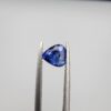 Studio close-up photographs showing the top table and facet profile views of a 1.26 carat pear cut natural blue sapphire loose gemstone held in precision tweezers.