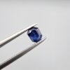 Studio close-up photographs showing the top table and step-cut profile views of a 1.00 carat octagon cut natural blue sapphire loose gemstone held in precision tweezers.