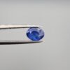 Studio close-up photographs showing the top table and side facet profile views of a 2.44 carat oval cut natural blue sapphire loose gemstone held in precision tweezers.