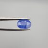 Studio close-up photographs showing the top table and side facet profile views of a 3.64 carat oval cut natural blue sapphire loose gemstone held in precision tweezers.