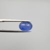 Studio close-up photographs showing the top table and side facet profile views of a 3.64 carat oval cut natural blue sapphire loose gemstone held in precision tweezers.