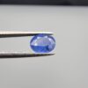 Studio close-up photographs showing the top table and side facet profile views of a 2.17 carat oval cut natural blue sapphire loose gemstone held in precision tweezers.