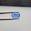 Studio close-up photographs showing the top table and side facet profile views of a 2.17 carat oval cut natural blue sapphire loose gemstone held in precision tweezers.
