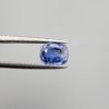 Studio close-up photographs showing the top table and side facet profile views of a 1.97 carat cushion cut natural blue sapphire loose gemstone held in precision tweezers.