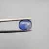 Studio close-up photographs showing the top table and side facet profile views of a 1.97 carat cushion cut natural blue sapphire loose gemstone held in precision tweezers.