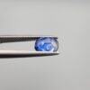 Studio close-up photographs showing the top table and side facet profile views of a 1.97 carat cushion cut natural blue sapphire loose gemstone held in precision tweezers.