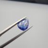 Studio close-up photographs showing the top table view with internal inclusions and reverse facet profile of a 1.41 carat pear cut natural blue sapphire loose gemstone held in precision tweezers.