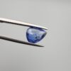 Studio close-up photographs showing the top table view with internal inclusions and reverse facet profile of a 1.41 carat pear cut natural blue sapphire loose gemstone held in precision tweezers.