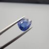 Studio close-up photographs showing the top table view with internal inclusions and reverse facet profile of a 1.41 carat pear cut natural blue sapphire loose gemstone held in precision tweezers.