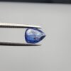 Studio close-up photographs showing the top table view with internal inclusions and reverse facet profile of a 1.41 carat pear cut natural blue sapphire loose gemstone held in precision tweezers.