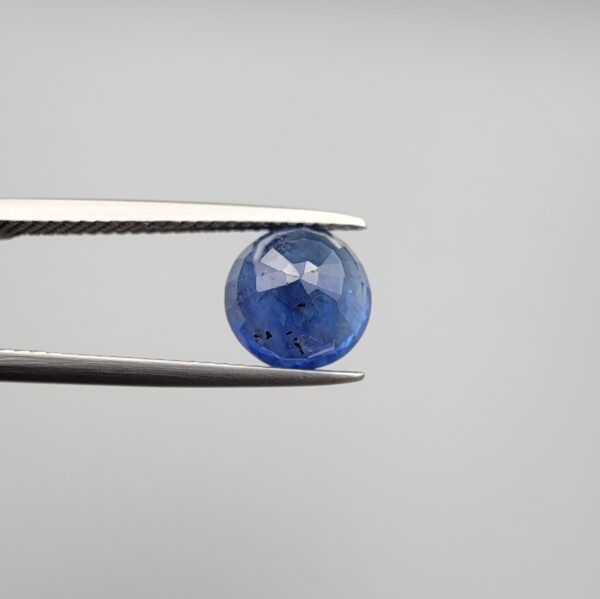 Studio close-up photographs showing the top table face and reverse natural mountain formation features of a 3.17 carat round cut natural blue sapphire loose gemstone held in precision tweezers.