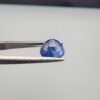 Studio close-up photographs showing the top table face and reverse natural mountain formation features of a 3.17 carat round cut natural blue sapphire loose gemstone held in precision tweezers.