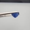 Studio close-up photographs showing the top table face and reverse natural mountain formation features of a 3.17 carat round cut natural blue sapphire loose gemstone held in precision tweezers.