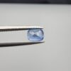 Studio close-up photographs showing the top table face and reverse facet profile of a 1.05 carat cushion cut natural blue sapphire loose gemstone held in precision tweezers.