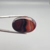 "Natural Carnelian Banded Agate Sulemani Aqeeq gemstone 25.08 carat oval cabochon from Iran held in tweezers showing brown, black, and white natural bands"