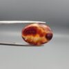 Studio close-up photographs showing the top dome face and reverse profile views of a 13.99 carat oval cabochon natural fire agate loose gemstone held in precision tweezers.