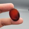 Studio close-up photographs showing the high-domed top surface, contrasting natural color bands, and finger-scale perspective views of a 60.66 carat oval cabochon natural Sulemani agate loose gemstone.