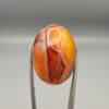 Studio close-up photographs showing the high-domed top surface, intricate concentric color banding, and reverse pattern views of a 56.58 carat dome-shaped natural chalcedony banded agate loose gemstone held in precision tweezers.