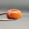 Studio close-up photographs showing the high-domed top surface, intricate concentric color banding, and reverse pattern views of a 56.58 carat dome-shaped natural chalcedony banded agate loose gemstone held in precision tweezers.