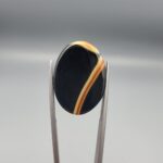 Studio close-up photographs showing the high-domed top surface, distinct natural "7" number pattern banding, and profile thickness views of a 21.69 carat oval cabochon Sulemani Aqeeq loose gemstone held in precision tweezers.