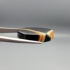 Studio close-up photographs showing the high-domed top surface, distinct natural "7" number pattern banding, and profile thickness views of a 21.69 carat oval cabochon Sulemani Aqeeq loose gemstone held in precision tweezers.