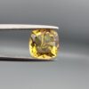 Studio close-up photographs showing the high-brilliance facet pattern, luminous golden body, and striking untreated internal rainbow light reflections of a 2.98 carat cushion cut natural citrine quartz loose gemstone held in precision tweezers.