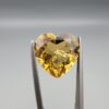Studio close-up photographs showing the high-brilliance facet pattern, romantic heart outline, luminous golden body, and striking sparkling untreated internal crystal inclusions of a 5.68 carat heart shape natural citrine quartz loose gemstone held in precision tweezers.