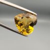 Studio close-up photographs showing the high-brilliance facet pattern, romantic heart outline, luminous golden body, and striking sparkling untreated internal crystal inclusions of a 5.68 carat heart shape natural citrine quartz loose gemstone held in precision tweezers.
