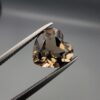 Studio close-up photograph showing the precision facet pattern, premium clarity, and rich brown color of a 3.33 carat heart shape brilliant cut natural smoky quartz loose gemstone held securely in tweezers.