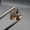 Studio close-up photograph showing the precision facet pattern, premium clarity, and rich brown color of a 3.33 carat heart shape brilliant cut natural smoky quartz loose gemstone held securely in tweezers.