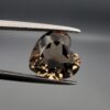 Studio close-up photographs showing the precision facet pattern, premium clarity, and rich brown color of a 3.29 carat heart shape brilliant cut natural smoky quartz loose gemstone held securely in tweezers.