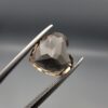 Studio close-up photographs showing the precision facet pattern, premium clarity, and rich brown color of a 3.29 carat heart shape brilliant cut natural smoky quartz loose gemstone held securely in tweezers.