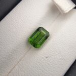 Studio close-up photograph showcasing the top-down view of an octagonal step-cut 2.14 carat natural vivid green tourmaline loose gemstone held securely in precision tweezers.
