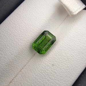 Studio close-up photograph showcasing the top-down view of an octagonal step-cut 2.14 carat natural vivid green tourmaline loose gemstone held securely in precision tweezers.