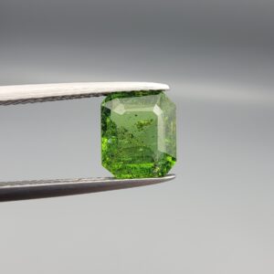Studio close-up photograph showcasing the top-down view of an octagonal step-cut 2.19 carat natural vivid green tourmaline loose gemstone held securely in precision tweezers.