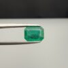 Studio close-up photograph showcasing an octagonal step-cut 1.97 carat natural green emerald gemstone held securely in precision tweezers.