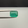 Studio close-up photograph showcasing an octagonal step-cut 1.97 carat natural green emerald gemstone held securely in precision tweezers.