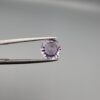 Studio close-up photographs displaying a 1.48-carat diamond-style cut natural amethyst Katela gemstone held securely in precision tweezers against a neutral grey background.
