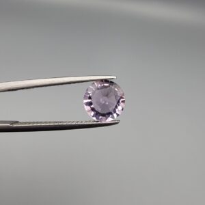 Studio close-up photographs displaying a 1.48-carat diamond-style cut natural amethyst Katela gemstone held securely in precision tweezers against a neutral grey background.