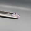 Studio close-up photographs displaying a 1.48-carat diamond-style cut natural amethyst Katela gemstone held securely in precision tweezers against a neutral grey background.